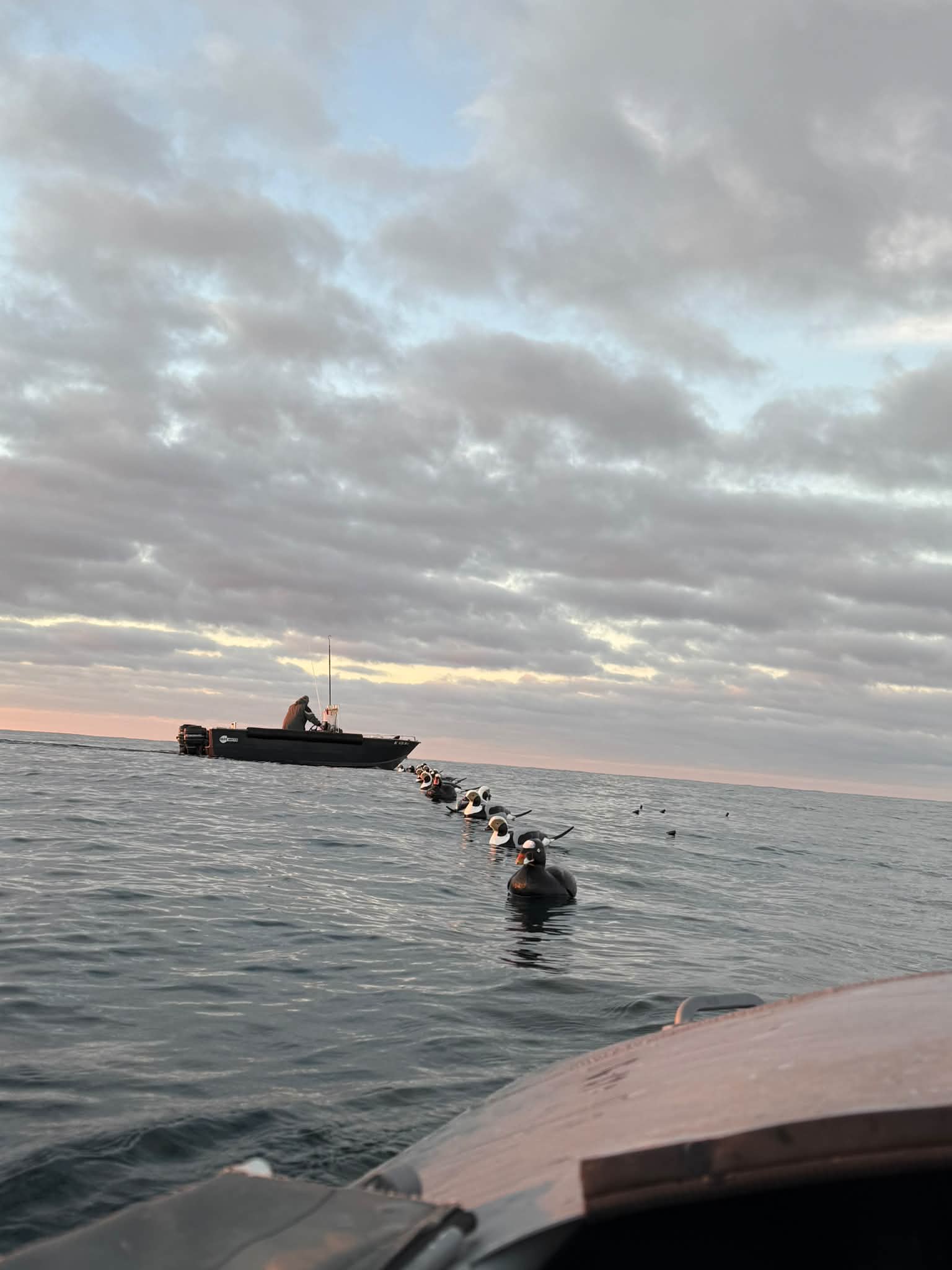 A fishing charter boat with clients in the water during sunset, showcasing Too Ez Sportfishing's active fishing operations on the Great Lakes.